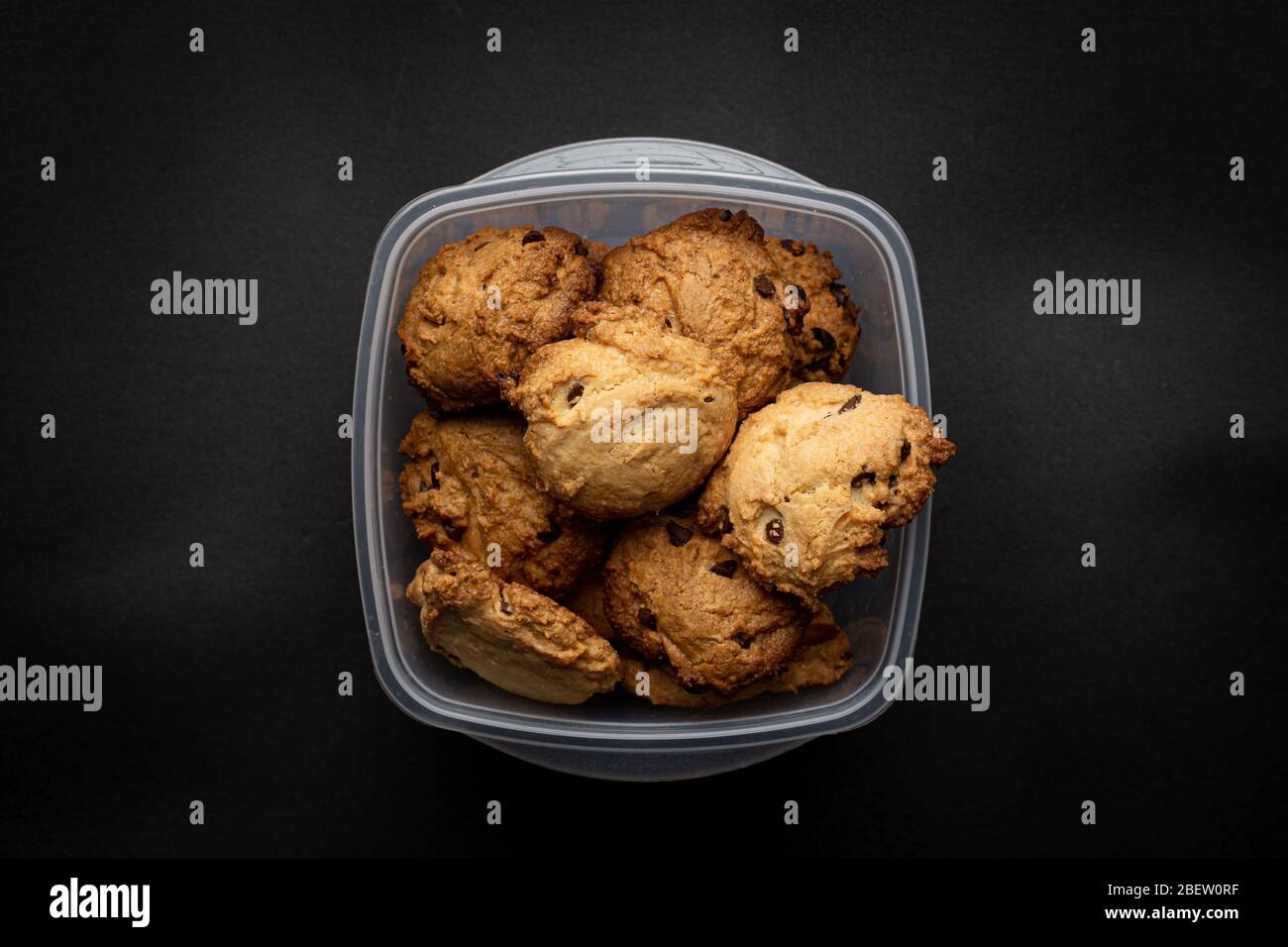 Homemade chocolate cookies on a plastic recipient on a dark grey background Stock Photo