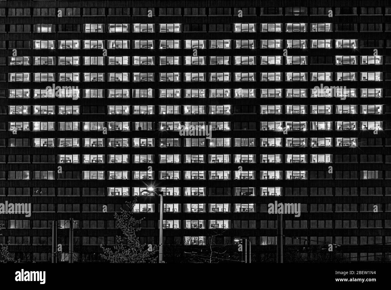 Heart shape illuminated windows of a building as a gesture for people who support others like now in hard corona virus times symbolically in black in Stock Photo
