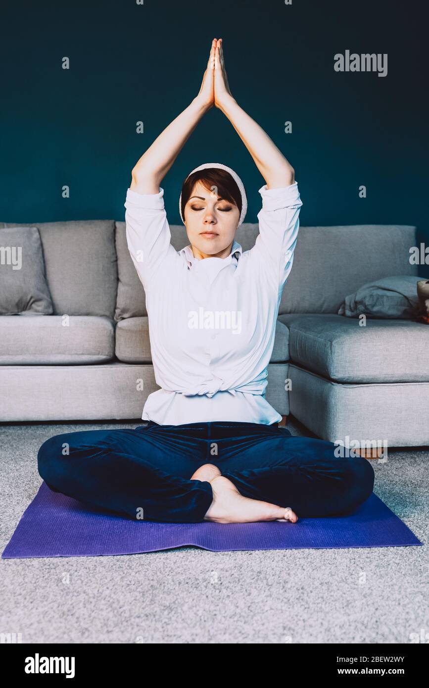 Woman is doing online yoga during self isolation at her living room, no equipment workout, meditation tips for beginners, stay home and stay healthy concept Stock Photo
