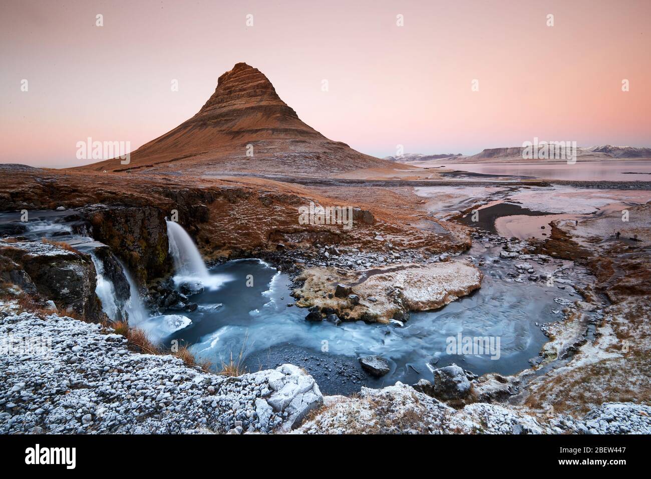 Kirkjufellsfoss, Iceland - Nov 27, 2019: Long exposure during sunset over the Kirkjufellsfoss Waterfall with Kirkjufell Mountain in the background in Stock Photo