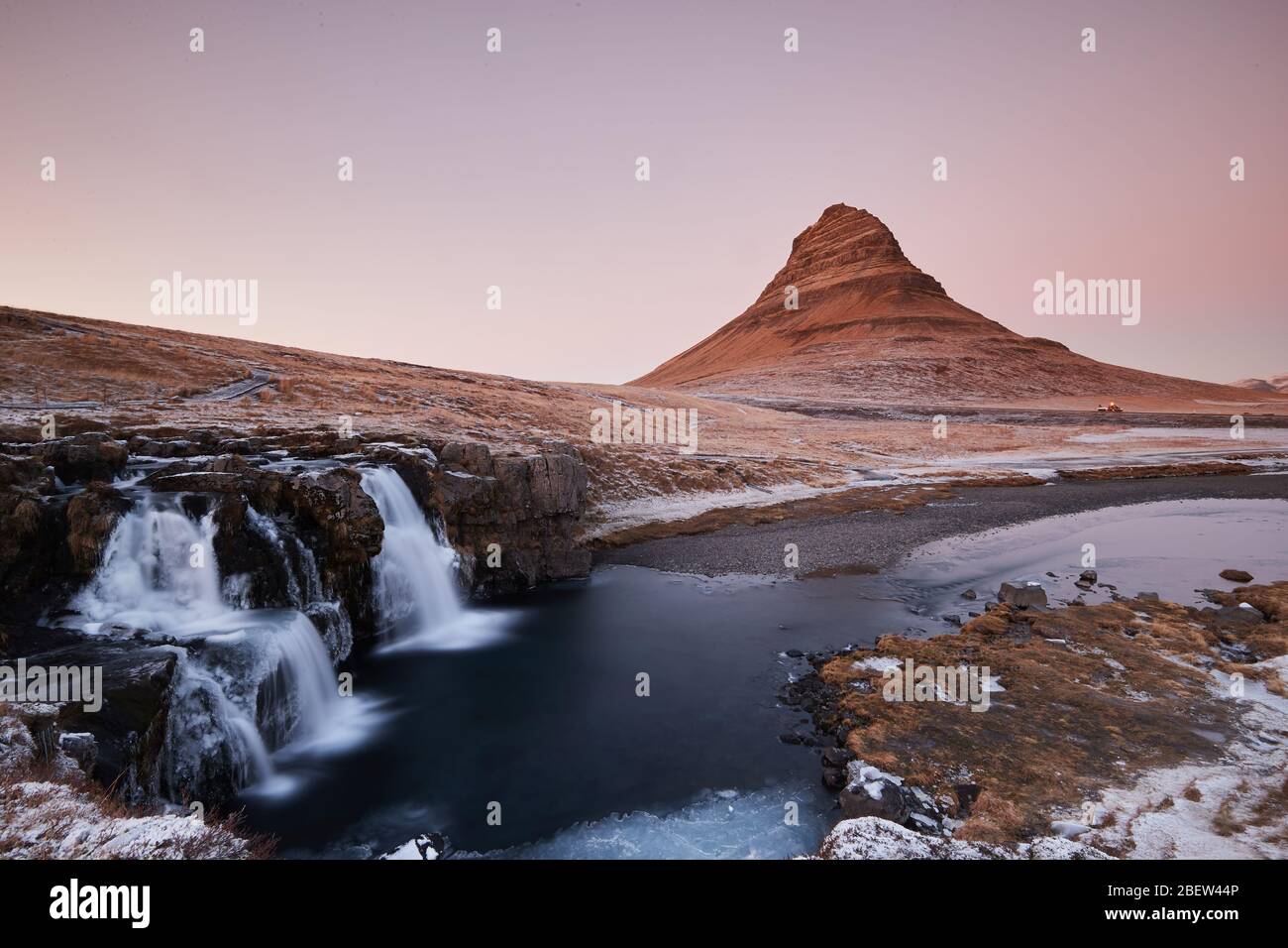 Kirkjufellsfoss, Iceland - Nov 27, 2019: Long exposure during sunset over the Kirkjufellsfoss Waterfall with Kirkjufell Mountain in the background in Stock Photo
