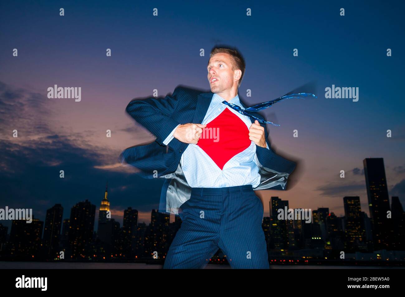 Businessman action hero arriving to save the day in front of a city skyline at night Stock Photo