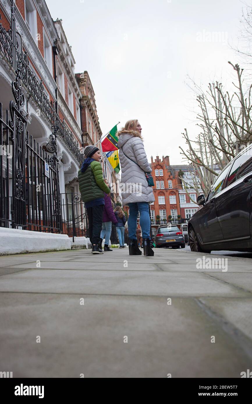 Mother and kids walking past St Kitts and Nevis High Commission, Kensington, London. Stock Photo