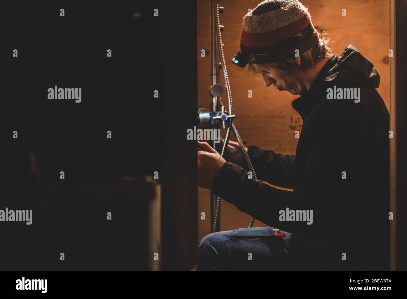 Side view of handyman working on installing a shower, bus conversion Stock Photo