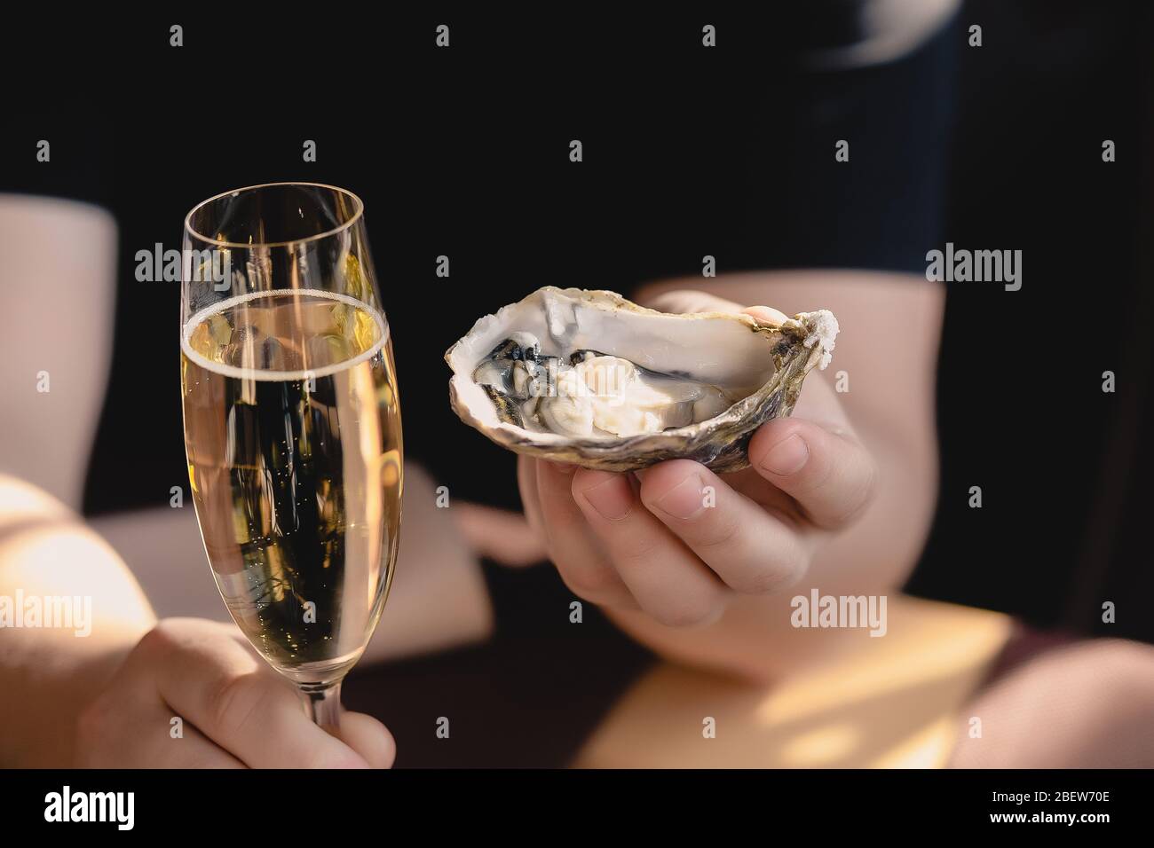 An oyster and a glass of champagne in the hand Stock Photo Alamy