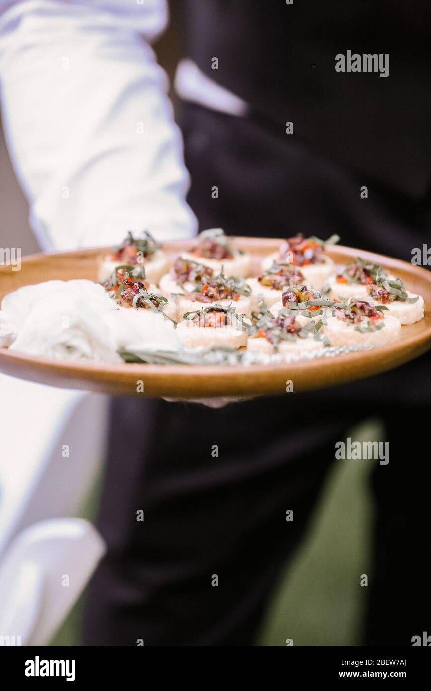 Passed Appetizers on wood tray in server's hand Stock Photo