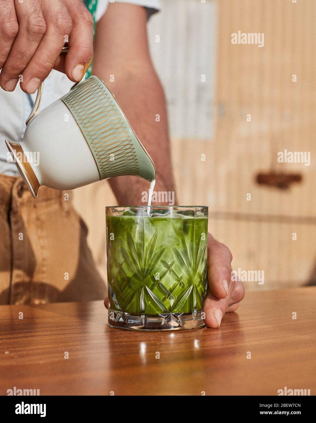 Pouring Coconut Milk into a Matcha Latte Stock Photo