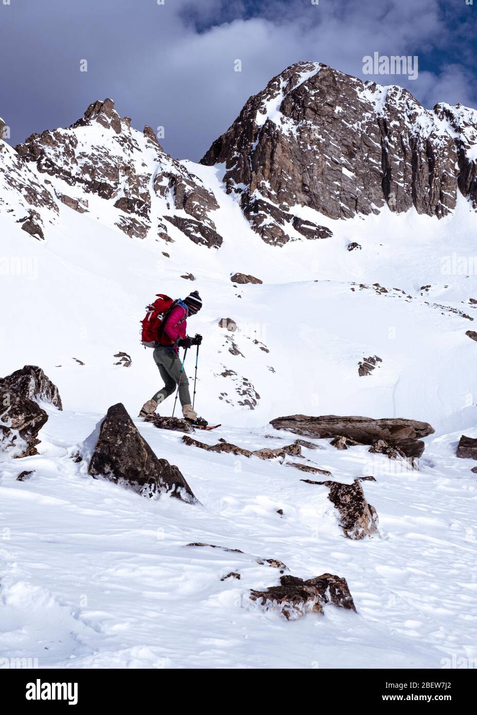 Woman snowshoe hiking in snow covered mountains in winter in Montana Stock Photo