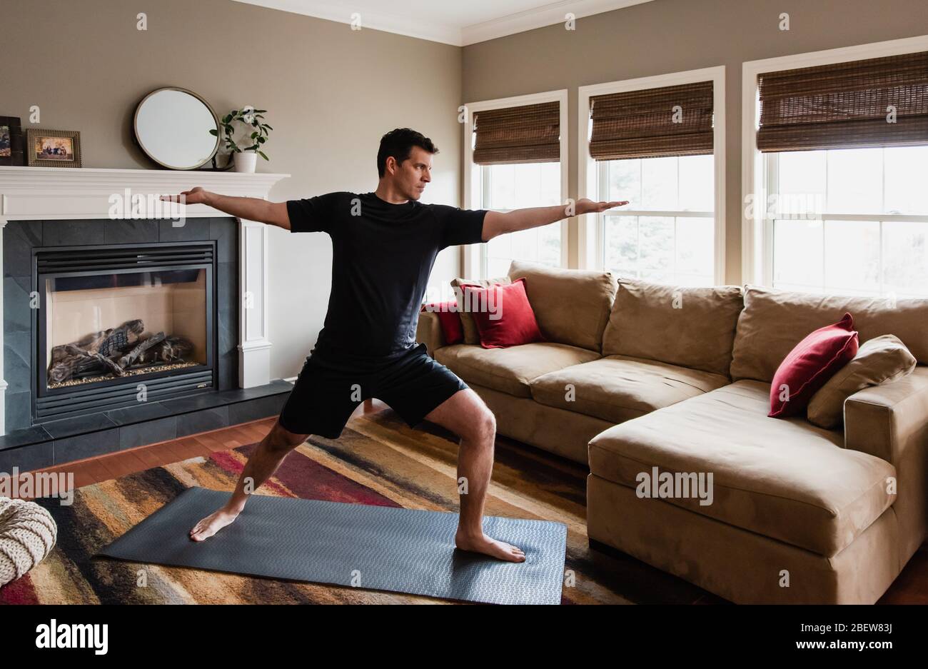 Fit man doing warrior yoga pose at home in his living room Stock Photo