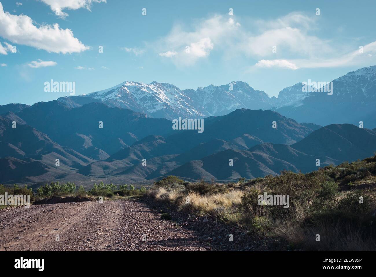 view of a dirt road and the Andes mountain range Nevada in Mendoza Arg Stock Photo