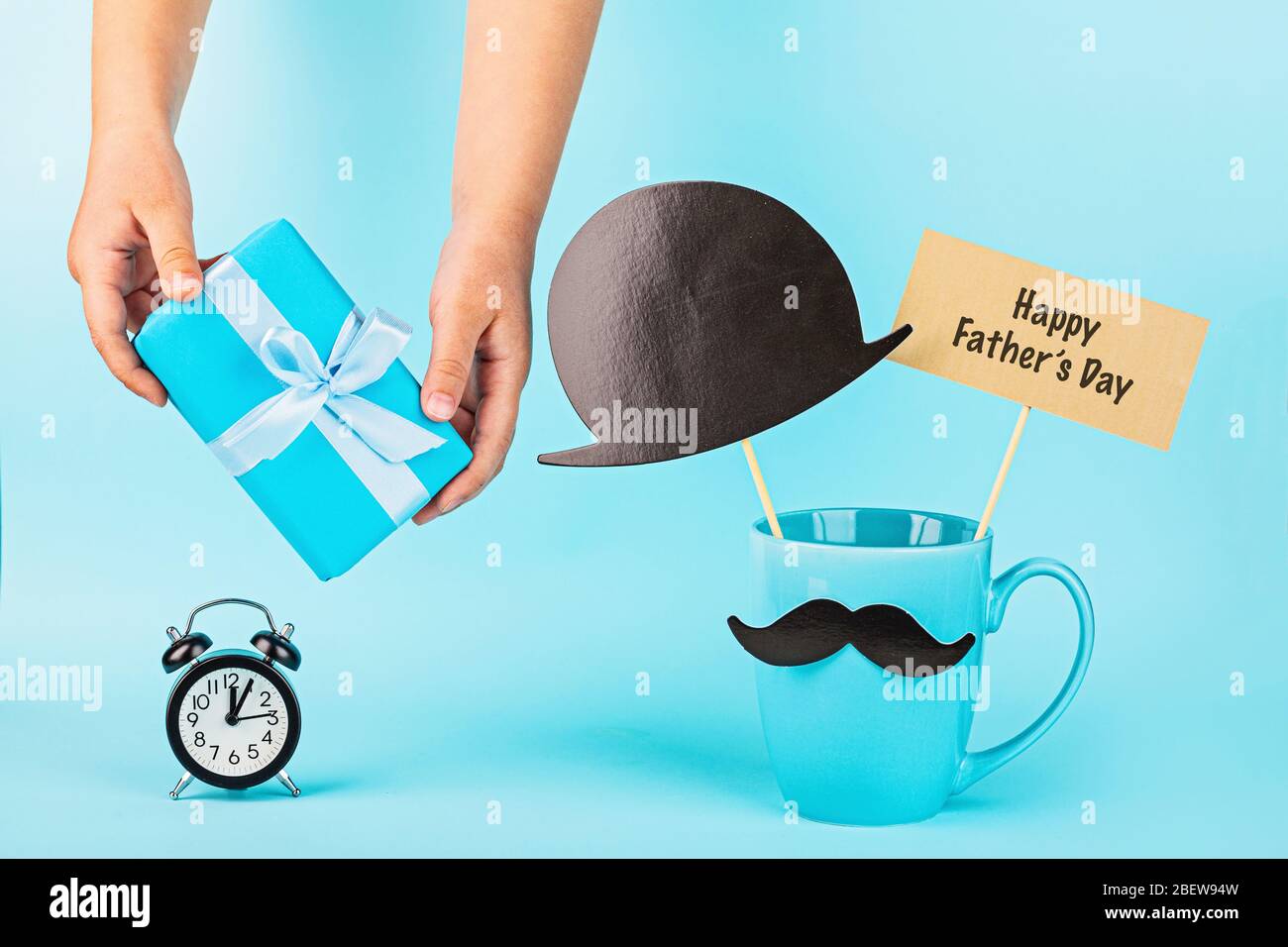 Download Happy Fathers Day Background Hands Holding Gift Box Alarm Clock Coffee Cup With Funny Moustache On Blue Table Mockup Template Greeting Card Stock Photo Alamy