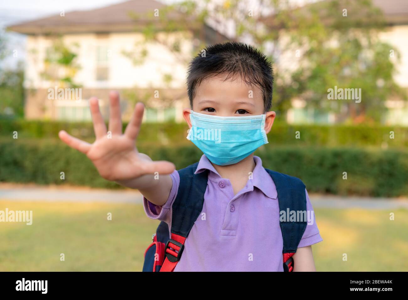 Little Asian boy wearing mask for protect pm2.5 and show stop hands gesture for stop corona virus outbreak. Covid-19 epidemic virus symptoms and Air p Stock Photo