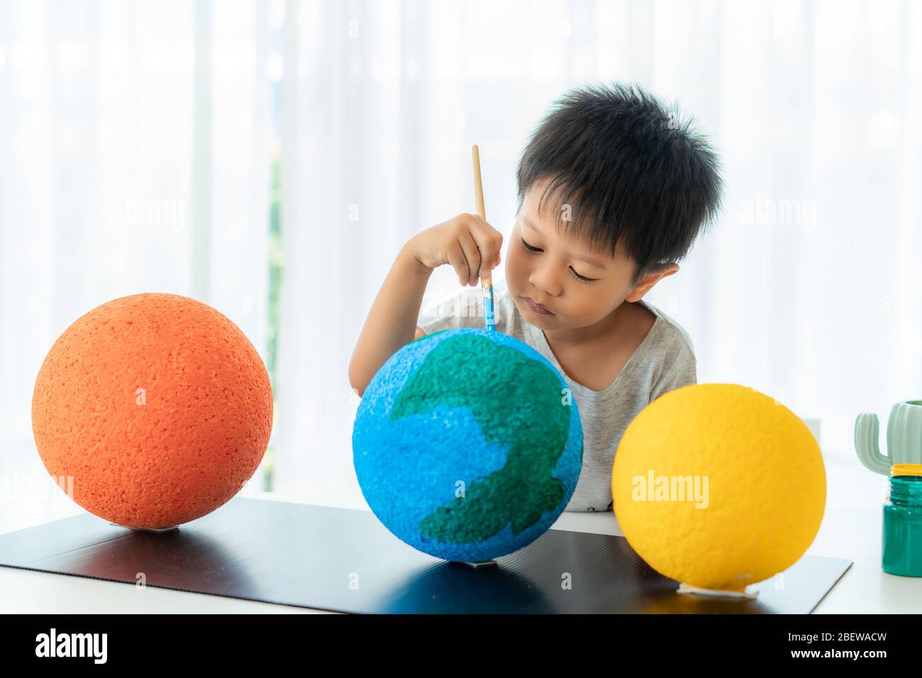 Asian preschool student boy painting the moon learning about the solar system at home, Homeschooling and distance learning. Stock Photo