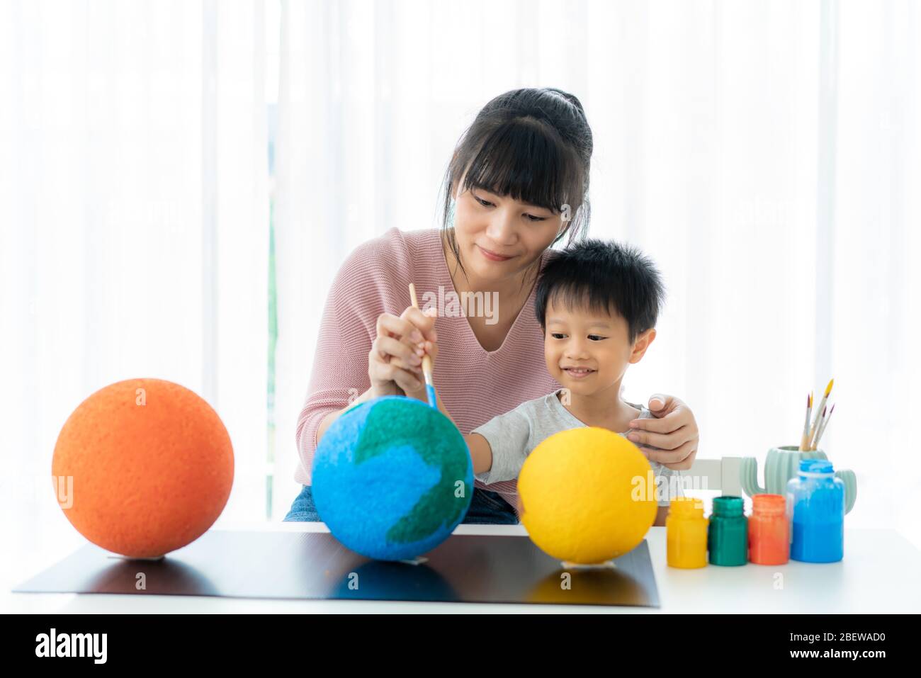 Asian preschool student boy with mother painting the moon learning about the solar system at home, Homeschooling and distance learning. Stock Photo
