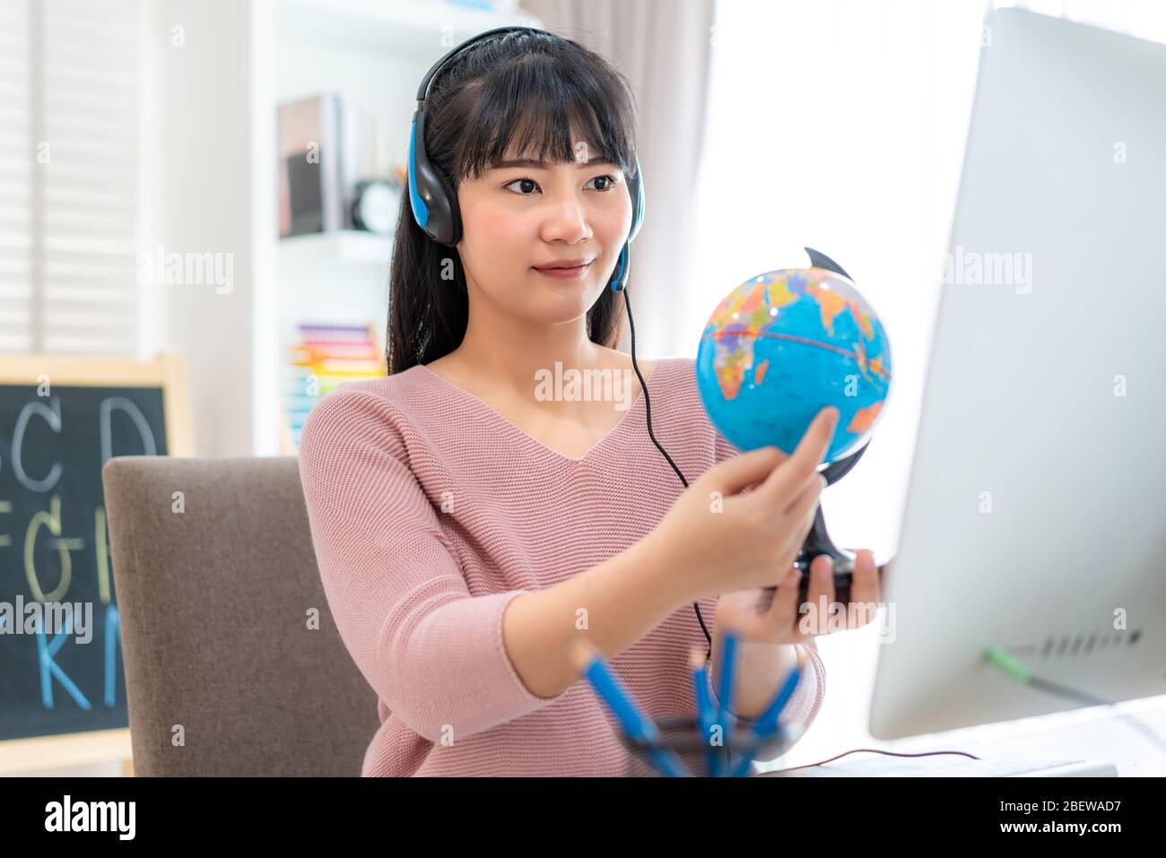 Asian woman teacher teaching geography via video conference e-learning and cheerful elementary school student looking at globe, Homeschooling and dist Stock Photo