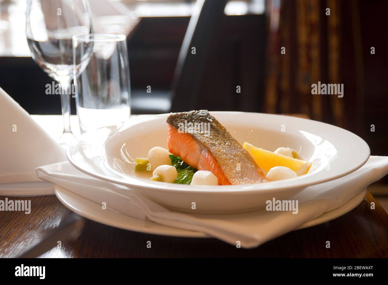 Plated salmon at a restaurant table place setting in fine dining restaurant Stock Photo