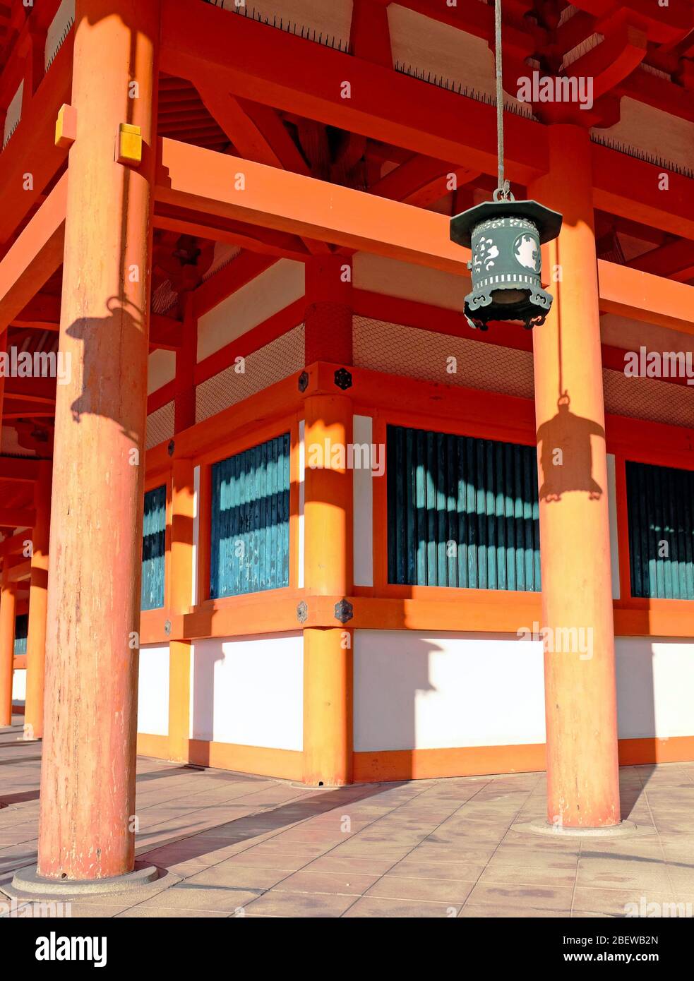 Tranquil Japanese setting in which old hanging Japanese lanterns cast shadows on the orange and green building in Kyoto, Japan. Stock Photo