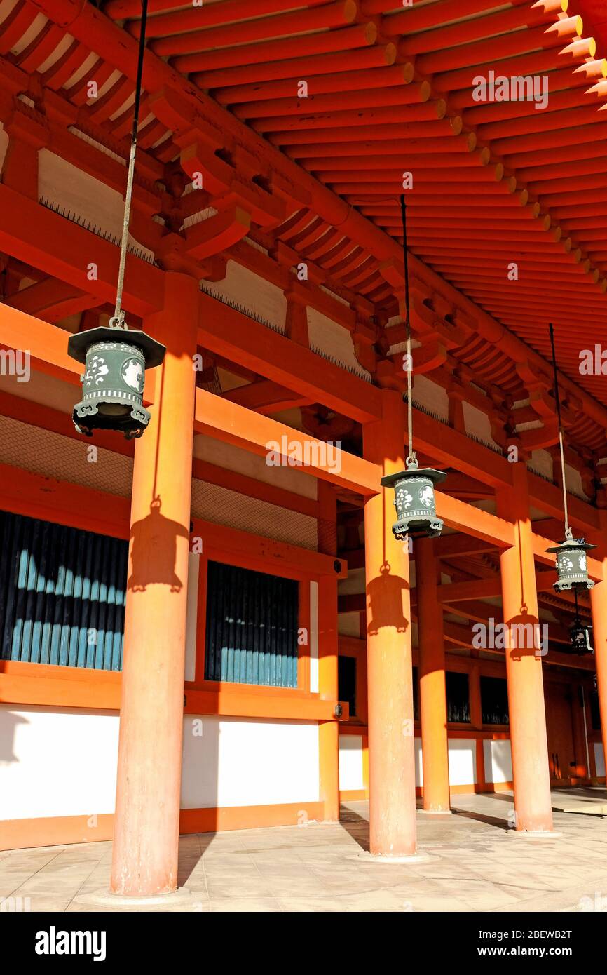Tranquil Japanese setting in which old hanging Japanese lanterns cast shadows on the orange and green building in Kyoto, Japan. Stock Photo