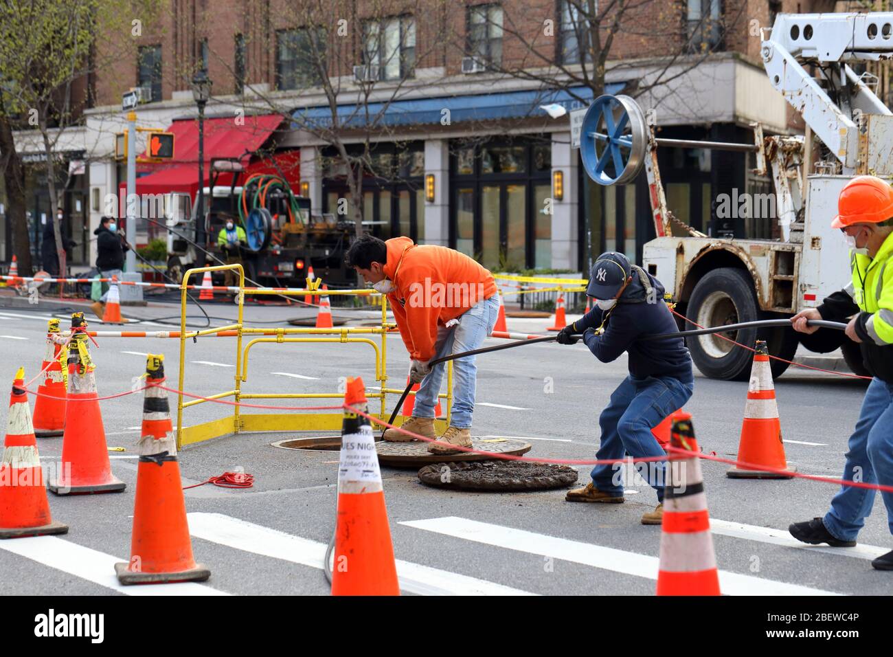 Workers pulling telecommunication cable from a manhole in Manhattan, New York, NY. Stock Photo
