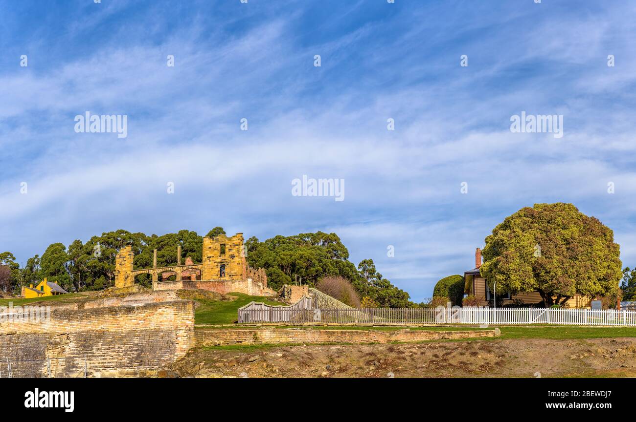 View of Smith O'Brians cottage, hospital ruins with stone wall surrounds next to wooden picket fence bordering the Canadian Cottage at Port Arthur. Stock Photo