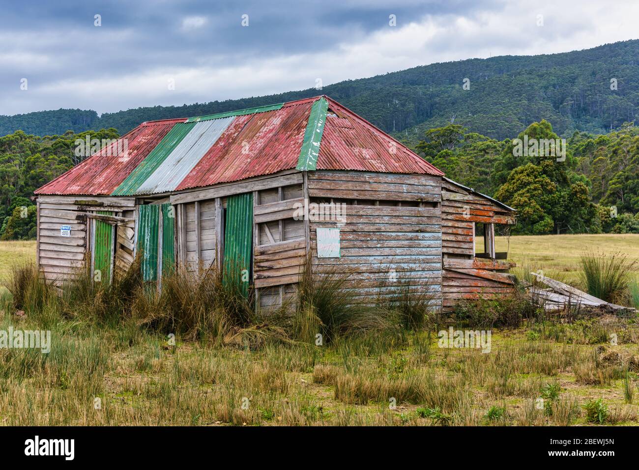 An abandoned, weatherboard and corrugated iron, pioneer settler farmhouse on a hillside along the east coast of Tasmania in Australia. Stock Photo