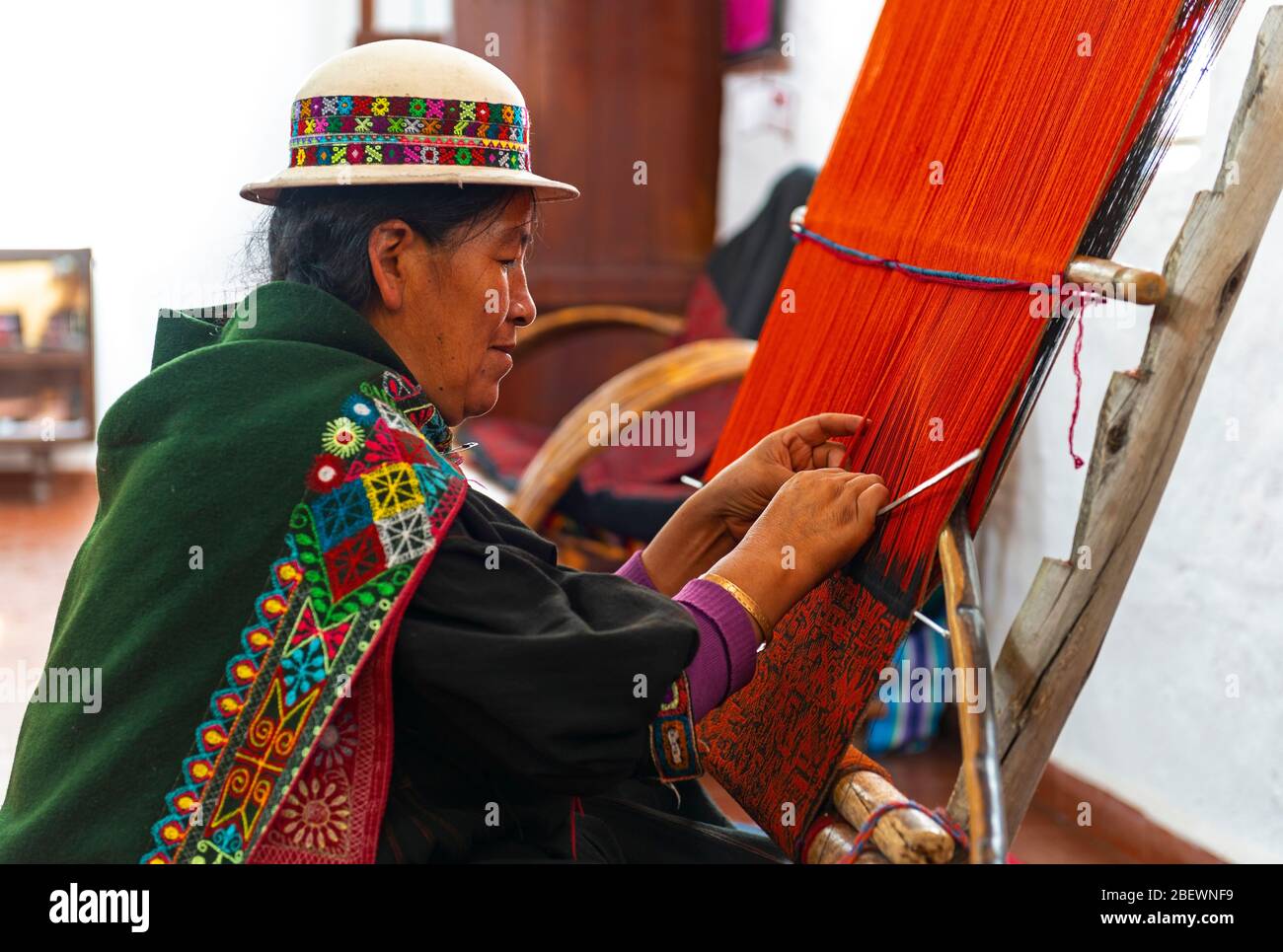 Indigenous senior woman in traditional clothing weaving a Jalq'a textile or fabric with ancient techniques, Sucre, Bolivia. Stock Photo
