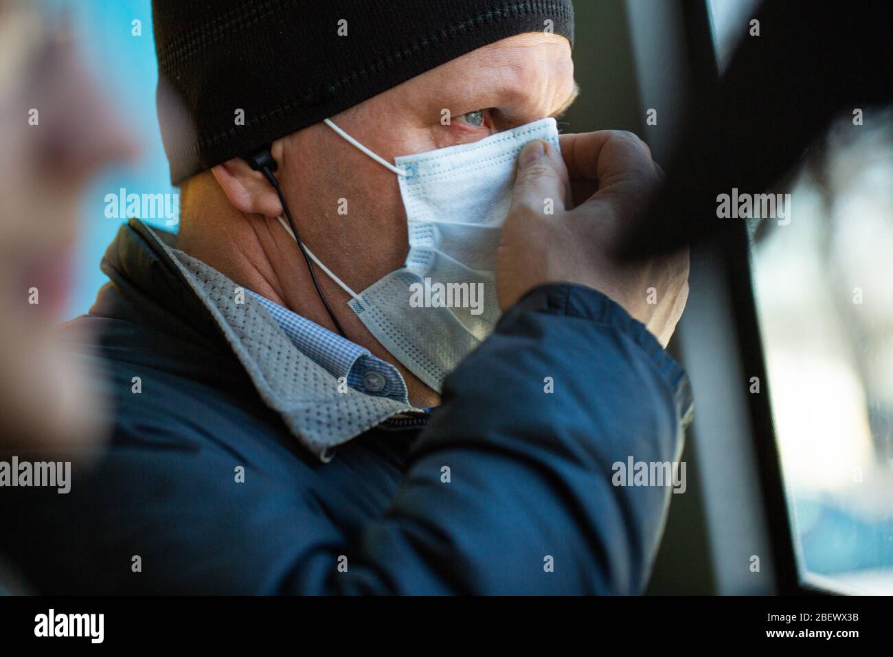 Vladivostok, Russia, March 24, 2020: a white man corrects his mask, stands on the bus during a pandemic outbreak of coronavirus. Stock Photo