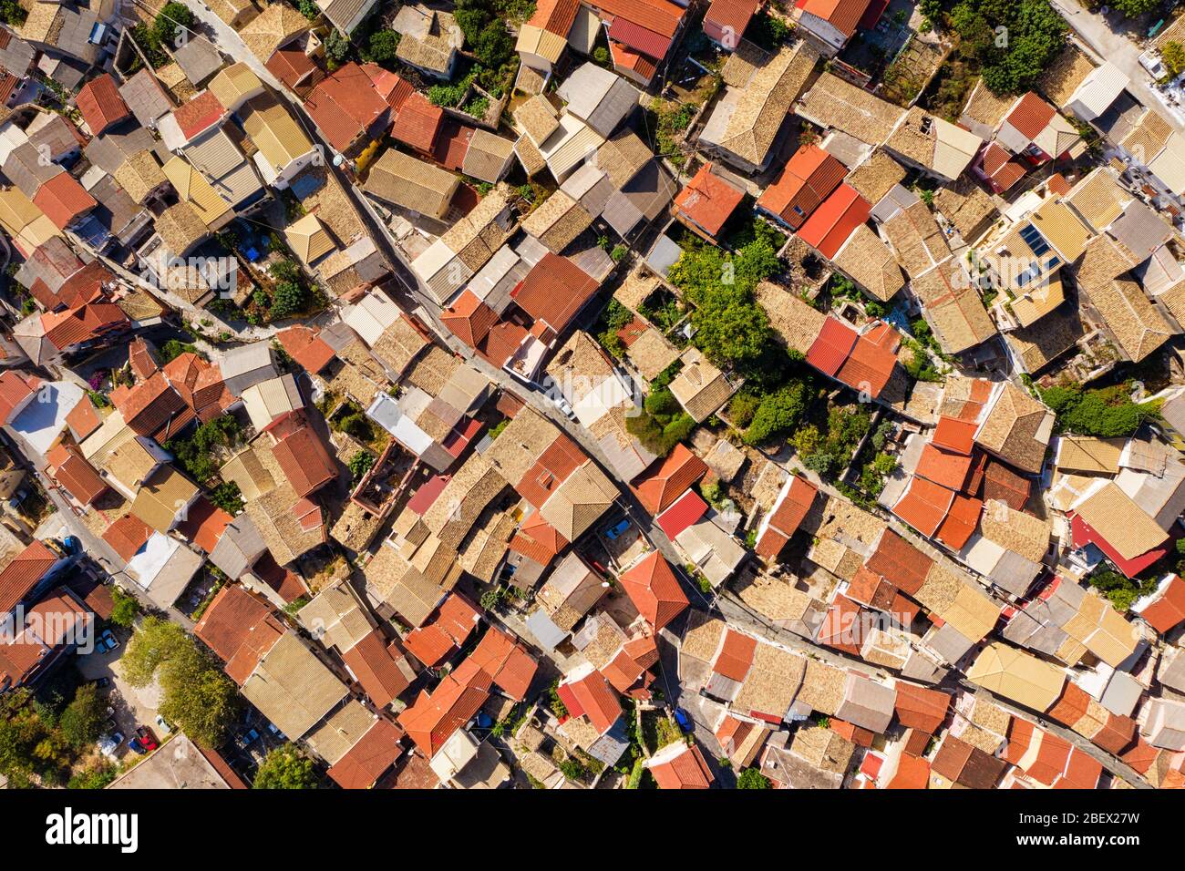 Bright tiled rooftops shot from a drone. Aerial of roof with red tiles in greek village. Old mediterranean architecture. Stock Photo