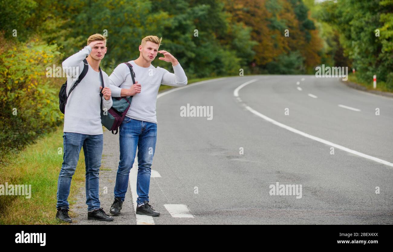 Budget travelers. men backpacks walking together by road. twins walking  along road. Adventure and discovery. Man with backpack hitchhiking on road.  Summer vacation. Tourist traveler travel auto stop Stock Photo - Alamy