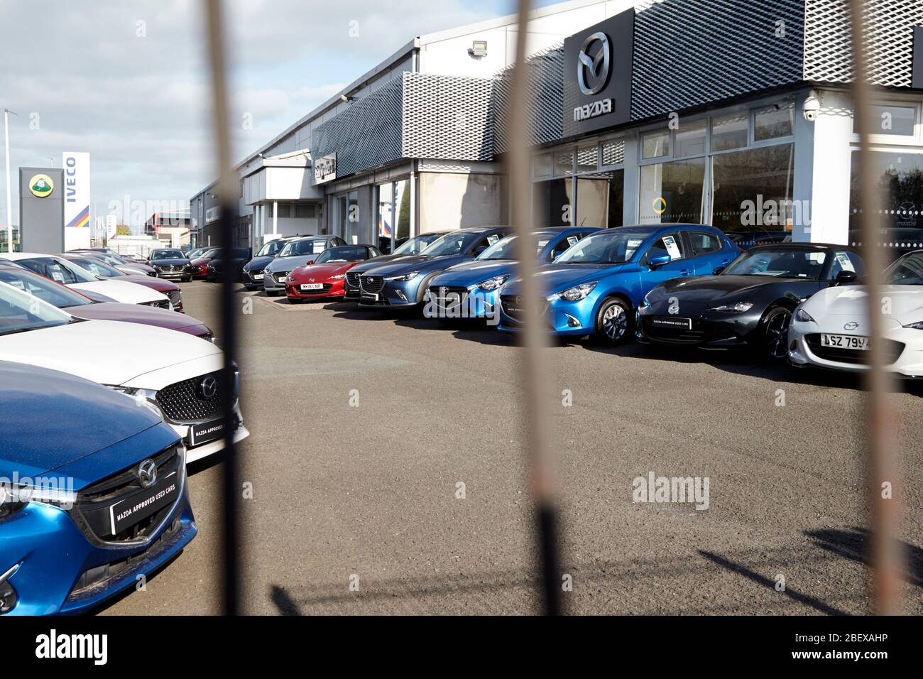 new and used cars unsold behind fence of closed car dealership due to coronavirus lockdown Newtownabbey Northern Ireland UK Stock Photo