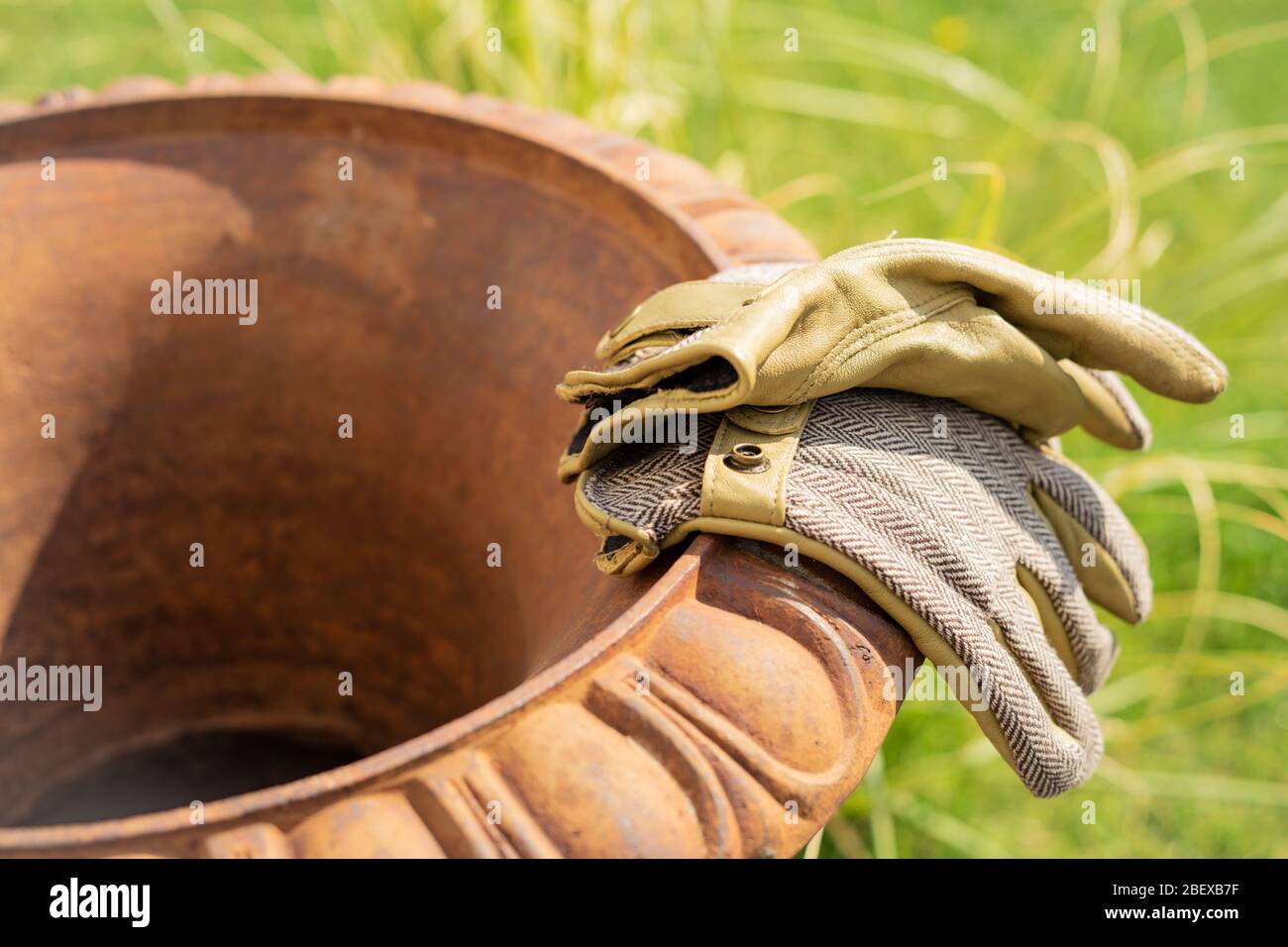 Garden gloves rest on the rim of a amphora after garden work is done Stock Photo
