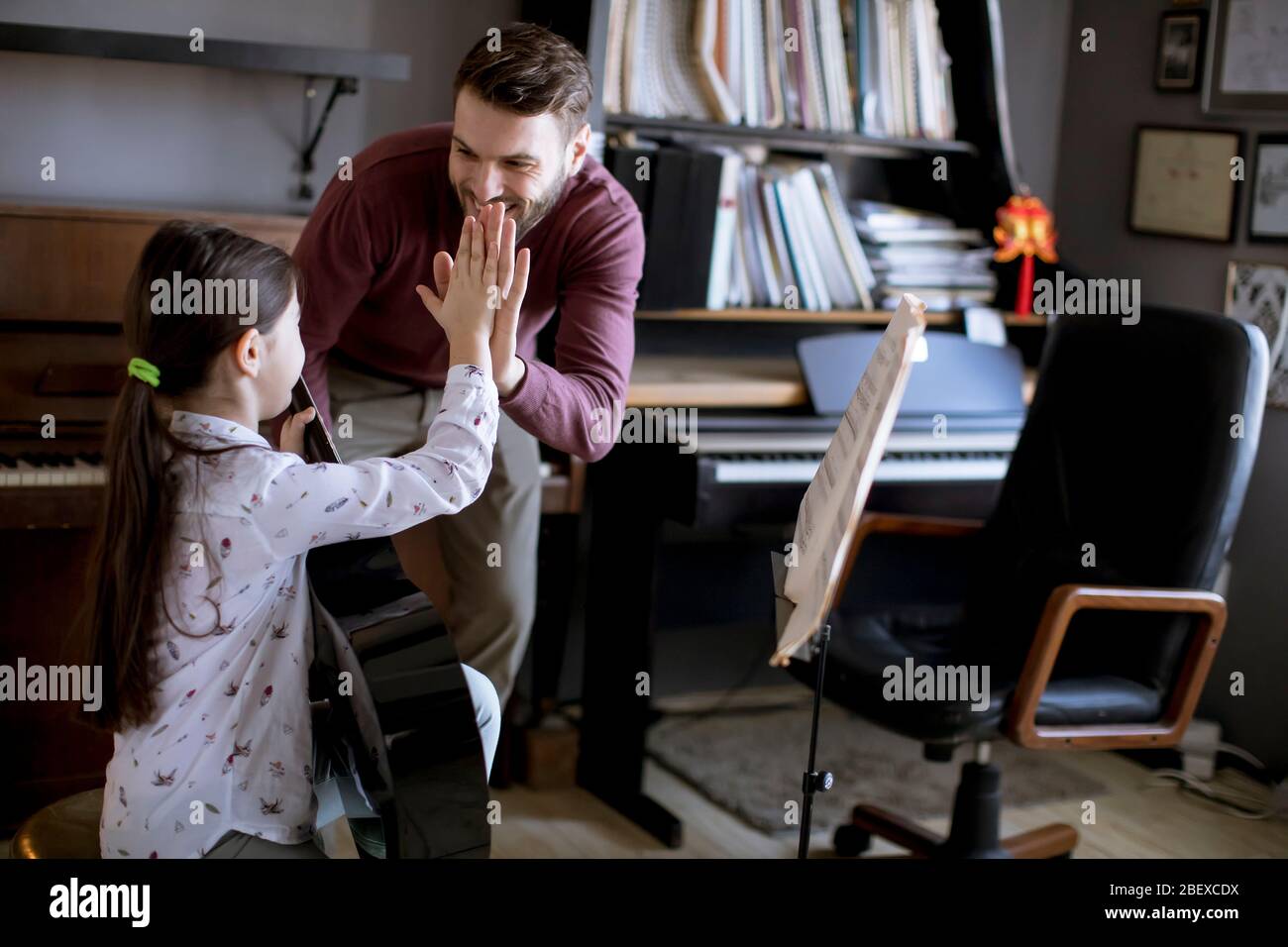 Cute little girl playing guitar with her music teacher in the rustic