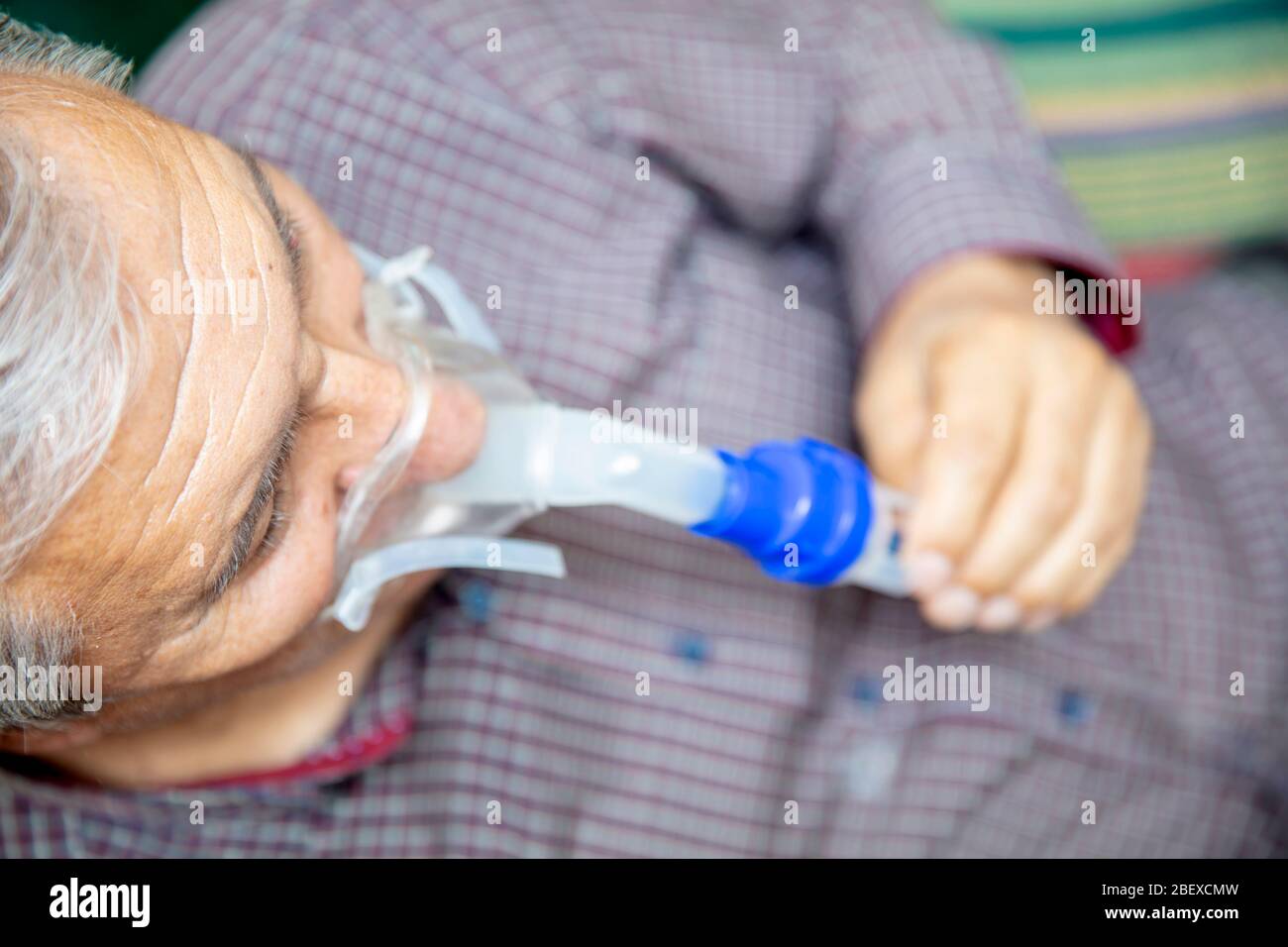 Senior man using medical equipment for inhalation with respiratory mask