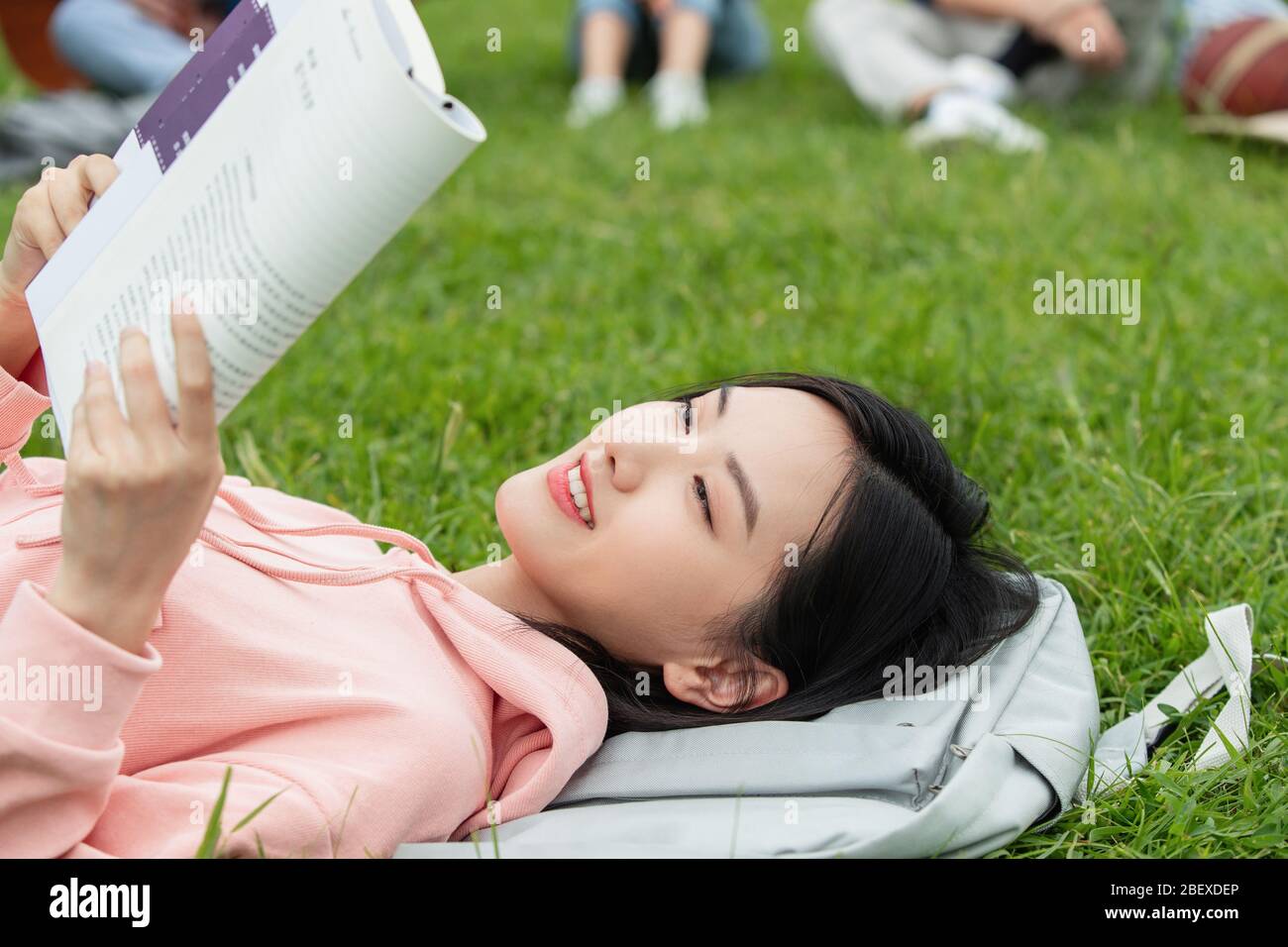 College students lay on the grass reading a book Stock Photo