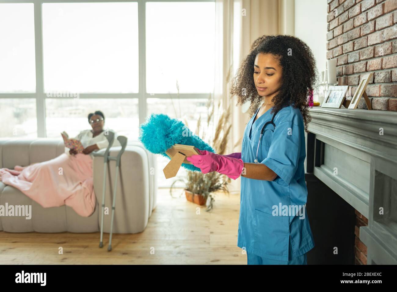 Skilled young nurse cleaning the dust from the photo Stock Photo