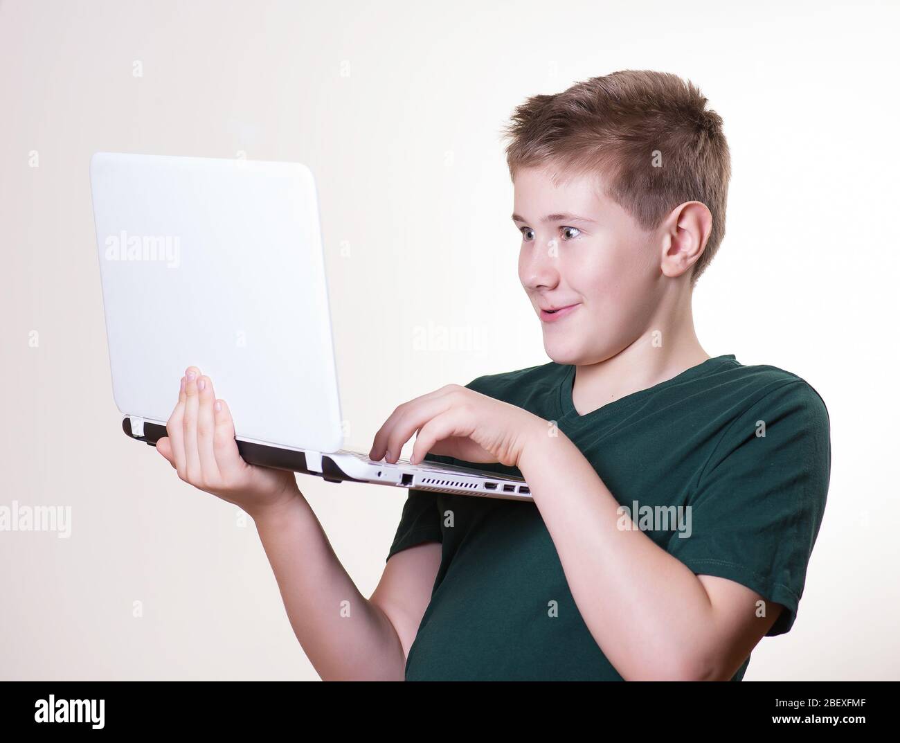 excited 10 - 12 years old boy (teenager) use his laptop Stock Photo