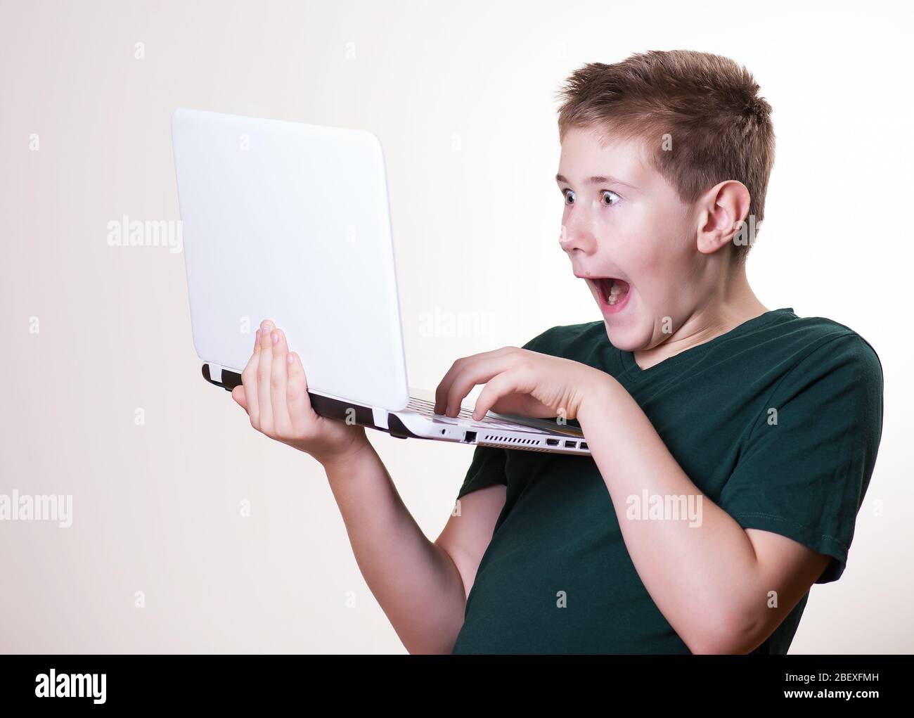 excited 10 - 12 years old boy (teenager) use his laptop Stock Photo