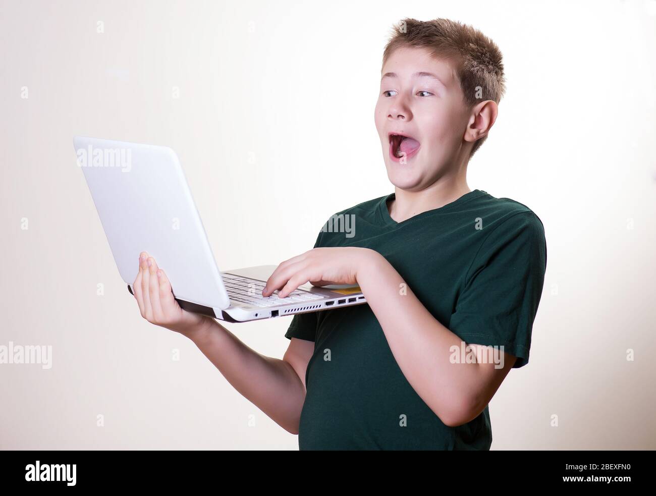 excited 10 - 12 years old boy (teenager) use his laptop Stock Photo
