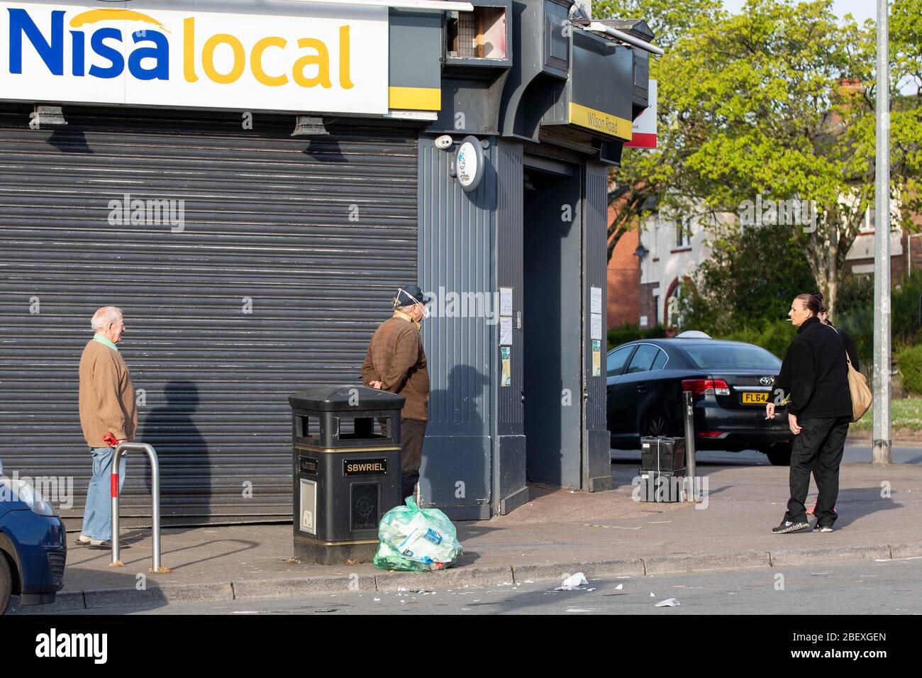 Cardiff, Wales, UK. 16th Apr, 2020. People observe social distancing as  they wait for a Nisa local store to be opened as shop workers wearing Nisa  fleeces smoke cigarettes in Ely, Cardiff,