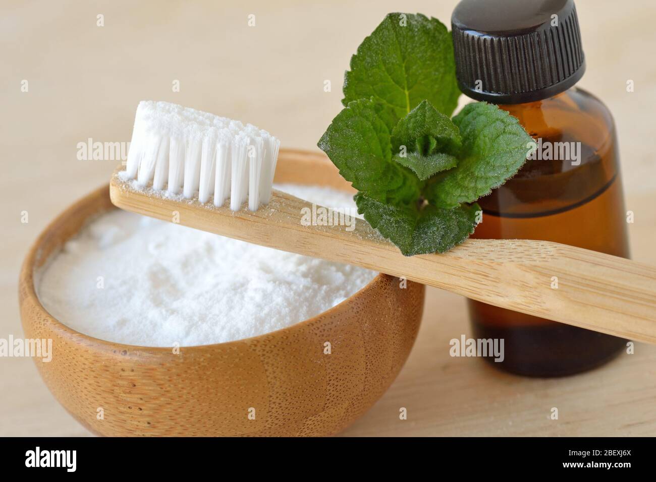 Baking soda in a bowl with a wooden toothbrush and peppermint essential oil  - Homemade natural toothpaste Stock Photo - Alamy