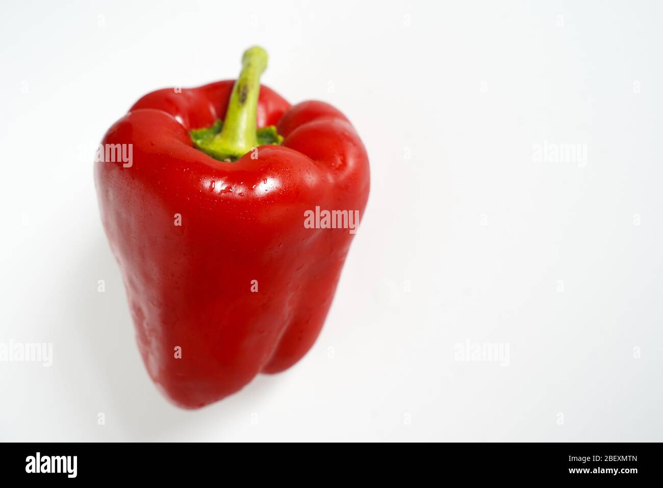 A whole red pepper on a plain white background Stock Photo