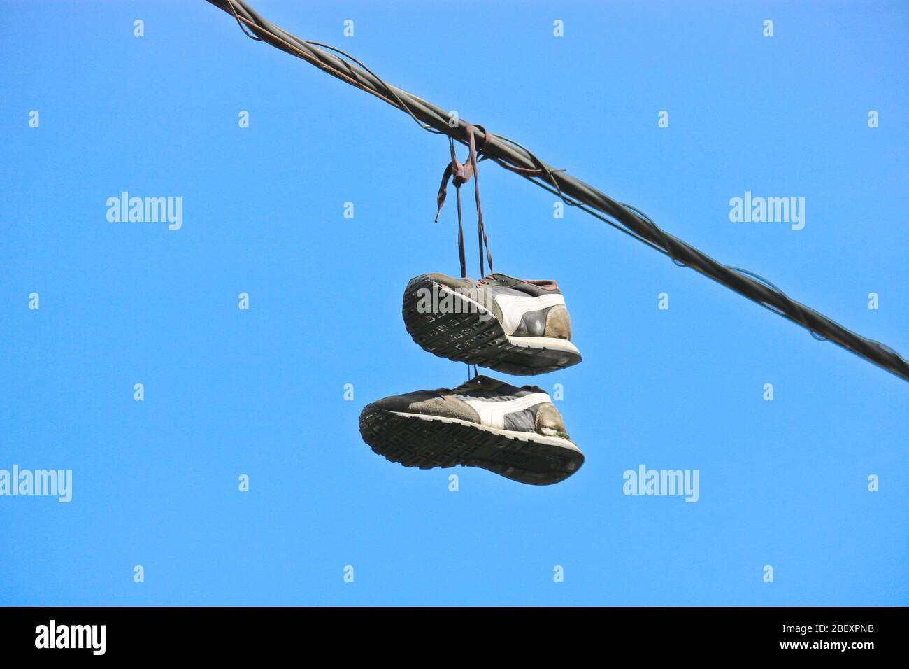 A pair of old sneakers on telephone wires in the city. Stock Photo