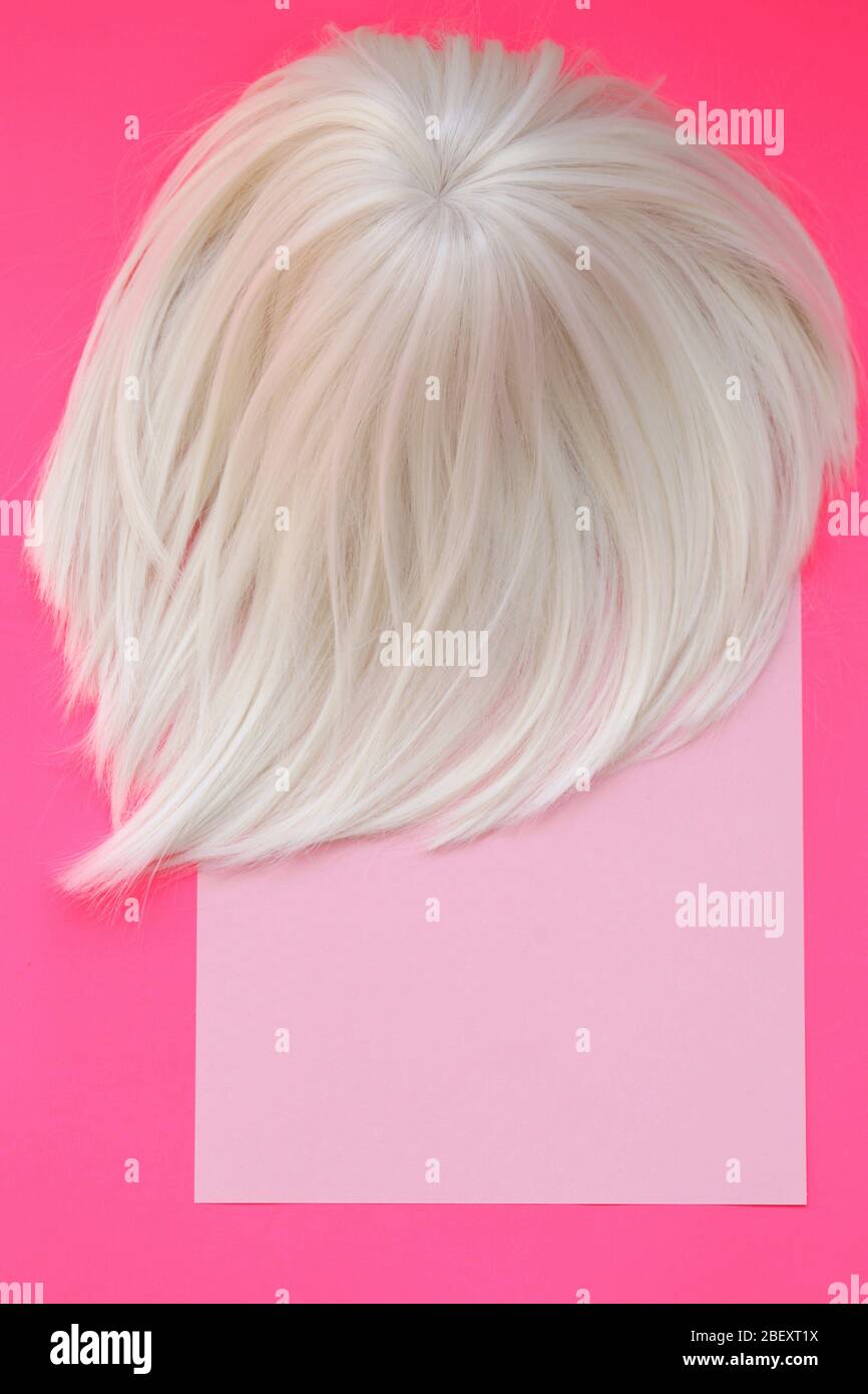 Blond hair. Cold silver ash blonde. Blonde hair colors. Care and coloring of hair in light shades. Wig blond on a pink background.copy space Stock Photo