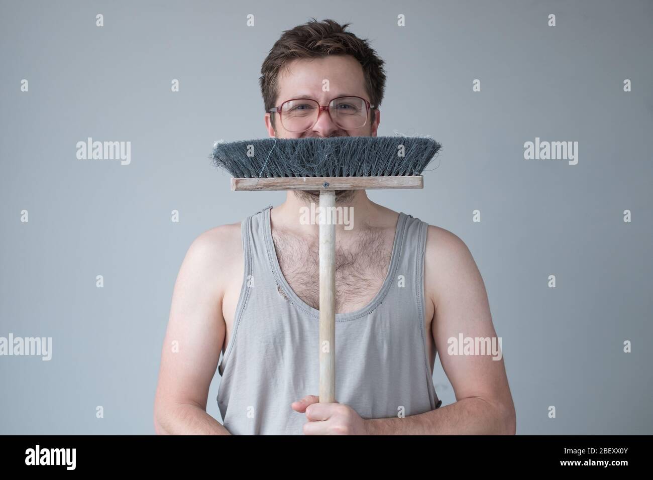 Young man standing ready for cleaning floor with mop. Studio shot Stock Photo