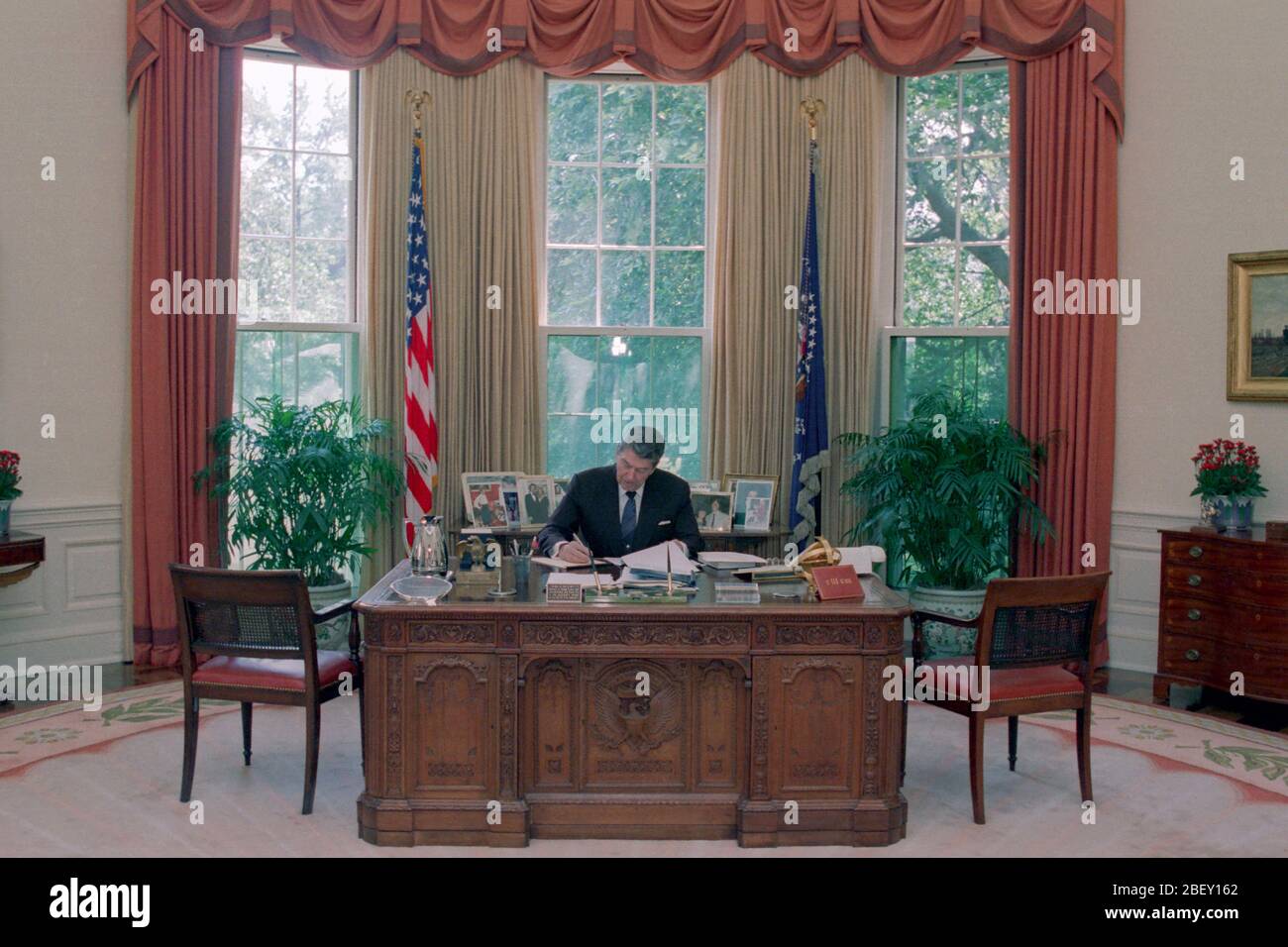 7/15/1988 President Reagan working at his desk in the Oval Office Stock Photo