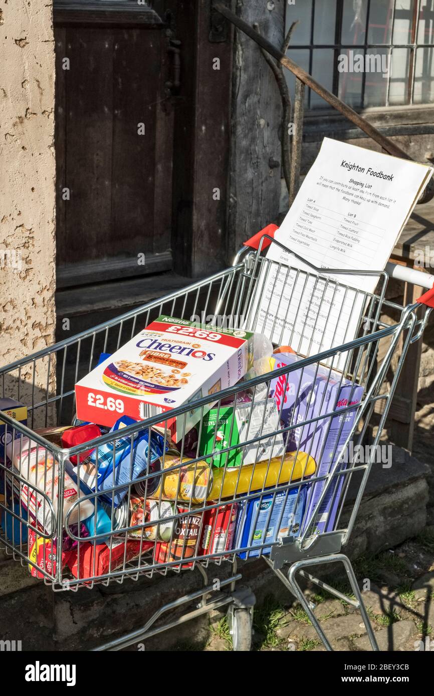 A shopping trolley on the high street in Presteigne, Powys, filled with groceries donated for the local food bank in nearby Knighton, Powys, Wales, UK Stock Photo