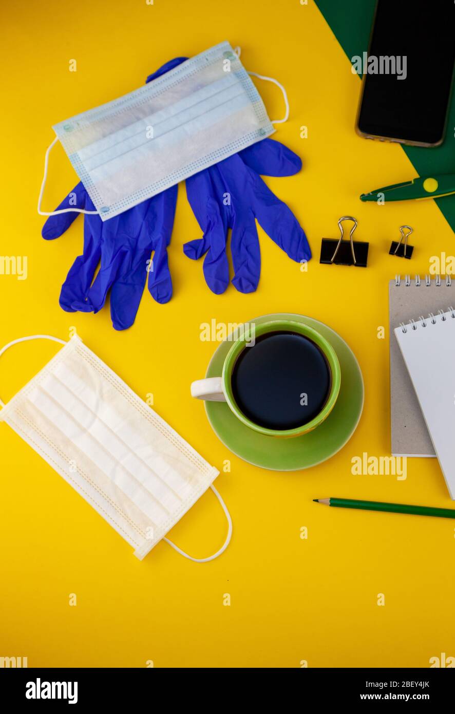 Working at home. Medical mask on the desktop. Remote work and study. Telework, freelance. Notepad with place for text and pen for notes. Layout Stock Photo