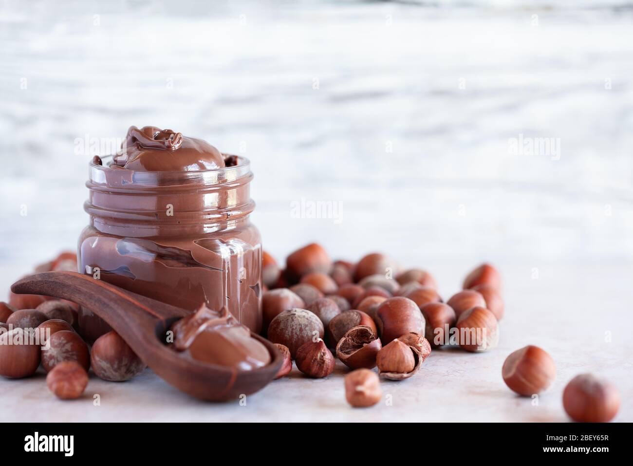 Fresh made homemade chocolate and hazelnut spread over a a white marble backdrop. Selective focus with extreme shallow depth of field and blurred back Stock Photo