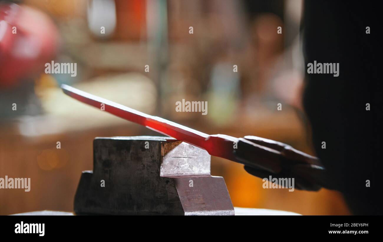 Making a knife out of hot metal using a pressure machine. Mid shot Stock Photo