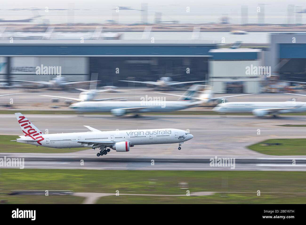 Lantau, Hong Kong  - April 10, 2020 :  Virgin Australia passenger airplane is landing in runway, all parking space is fully occupied because of COVID- Stock Photo